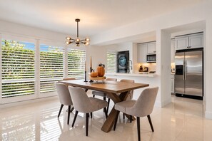 Una cocina moderna con una isla grande, armarios blancos y un refrigerador de acero inoxidable.