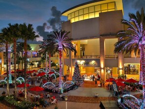 Un atrium d’hôtel agrémenté de palmiers, d’un sapin de Noël et d’espaces de détente en plein air.