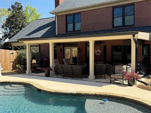 A house with a covered patio, a swimming pool, and outdoor furniture.