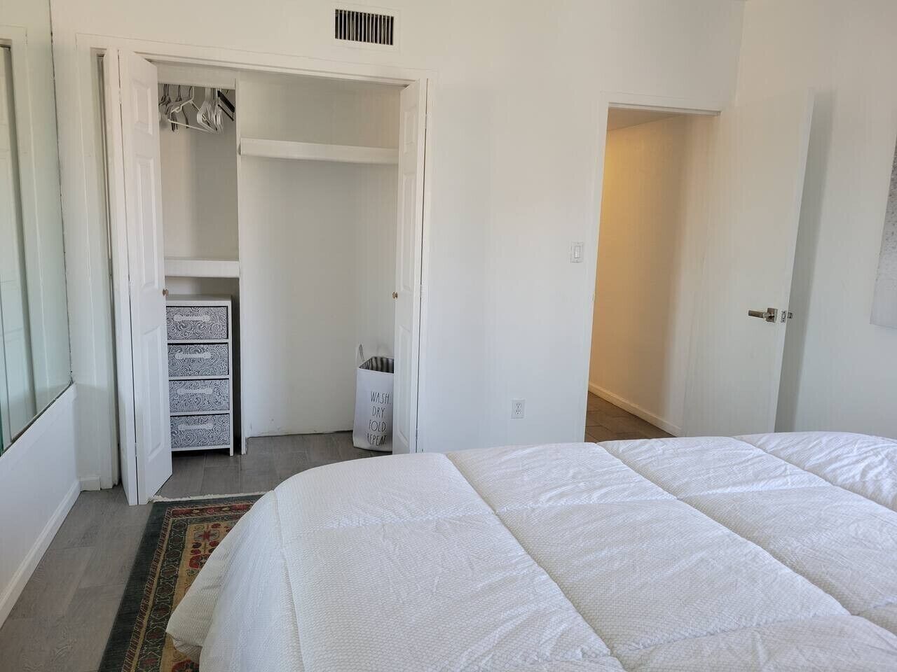 A bedroom with a bed, a wardrobe, and a small storage unit.