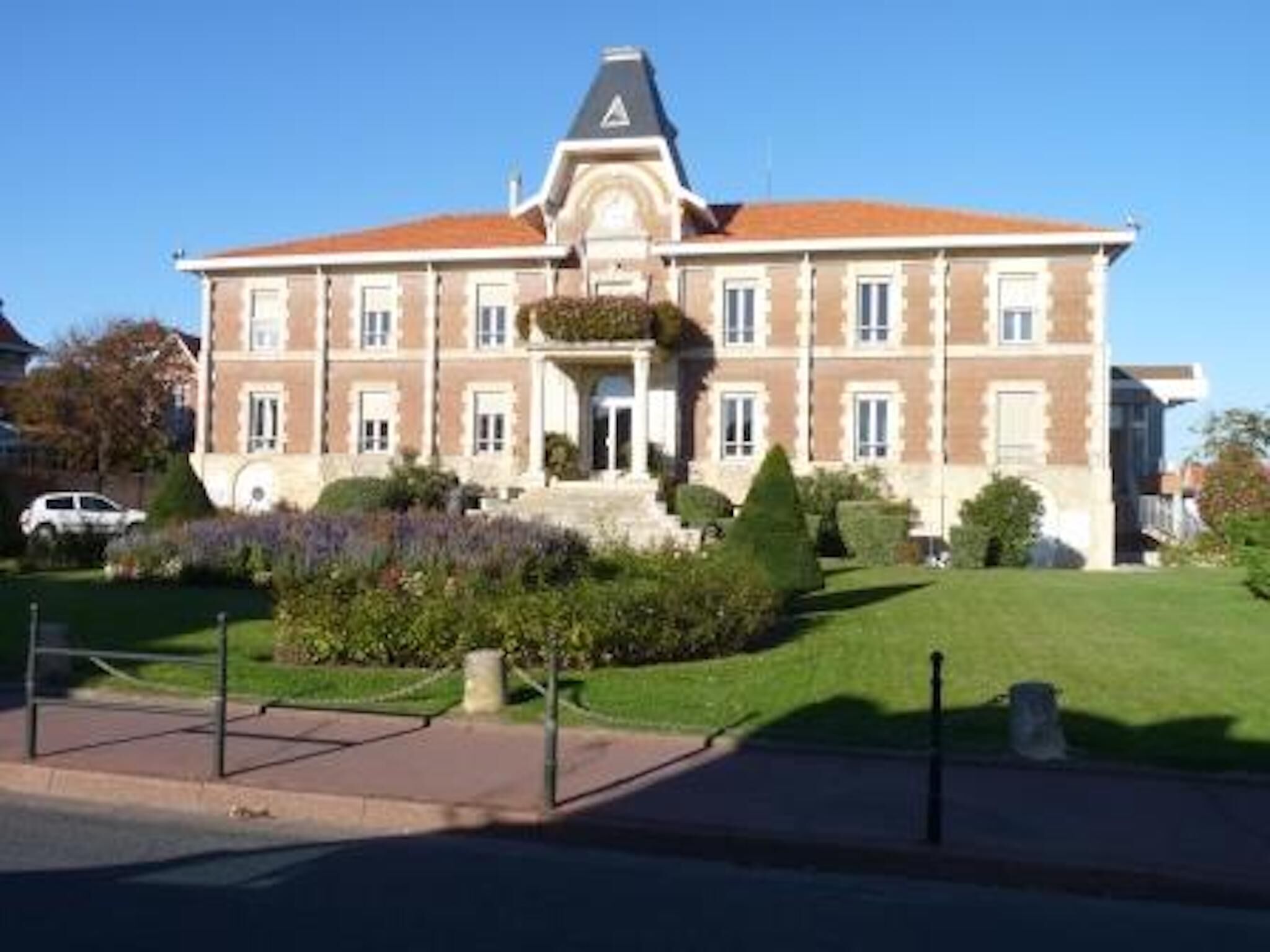 A large, two-story building with a symmetrical facade, a central entrance, and a triangular roof.