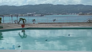 Een zwembad met uitzicht op een waterlichaam en bergen op de achtergrond.