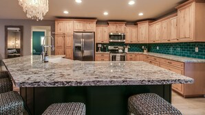 A kitchen with wooden cabinets, a stainless steel refrigerator, a microwave, and a granite island with bar stools. - Relaxing 4 Bdrm Retreat in the Heart of Scottsdale!  Big yard and Heated Pool!  (Scottsdale)