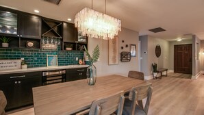 A modern kitchen with a wooden dining table, dark cabinets, and a green tiled backsplash. - Relaxing 4 Bdrm Retreat in the Heart of Scottsdale!  Big yard and Heated Pool!  (Scottsdale)