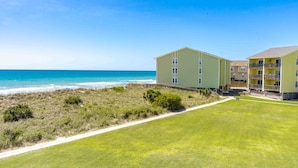 A beachfront hotel with a grassy lawn and a clear view of the ocean. - Ocean Vue - 1BR Surf Condo - Swimming Pool & Ocean Views! (Surf City)