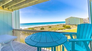 A covered outdoor area with a view of the beach, a table, and two chairs. - Ocean Vue - 1BR Surf Condo - Swimming Pool & Ocean Views! (Surf City)