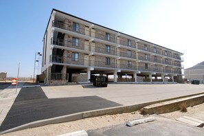 Een meerhoog gebouw met balkons en een parkeerplaats ervoor.