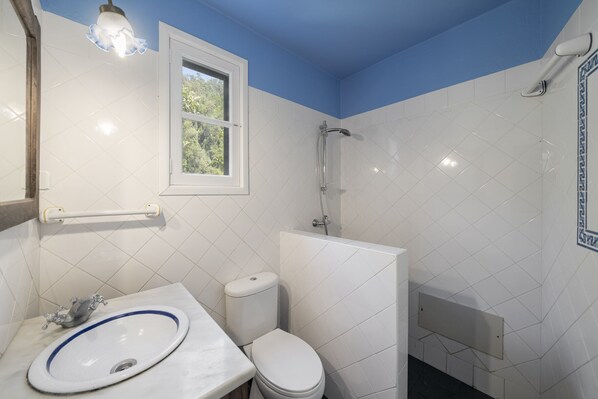A bathroom with a white sink, toilet, and shower.