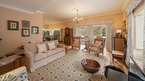 A living room with a patterned rug, a sofa, armchairs, a wooden coffee table, and a chandelier. - In Laurissilva Forest, Casa do Lanço -Carvalho (São Vicente)