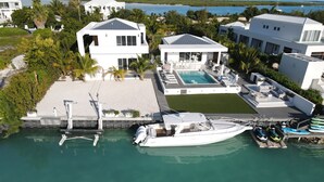 A modern waterfront property with a swimming pool, a boat dock, and a marina.