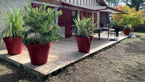 Une terrasse en bois agrémentée de plantes en pot, d’une table et d’une chaise.