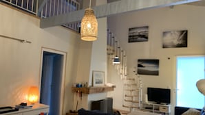 Un salon avec un canapé, une table à manger et des chaises, un téléviseur et un escalier.