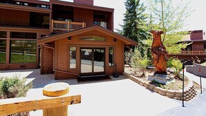 A wooden lodge with a front entrance, a balcony, and a large bear statue in the garden. - Slopeside remodeled mountain cabin ski in ski out! (Mammoth Lakes)