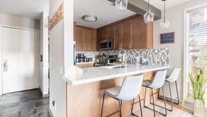 A modern kitchen with a large island, bar stools, and pendant lighting. - Slopeside remodeled mountain cabin ski in ski out! (Mammoth Lakes)