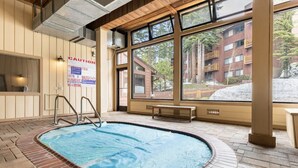 An indoor swimming pool with a wooden deck, large windows, and a caution sign. - Slopeside remodeled mountain cabin ski in ski out! (Mammoth Lakes)