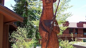 A wooden bear statue in a landscaped area with a building in the background. - Slopeside remodeled mountain cabin ski in ski out! (Mammoth Lakes)