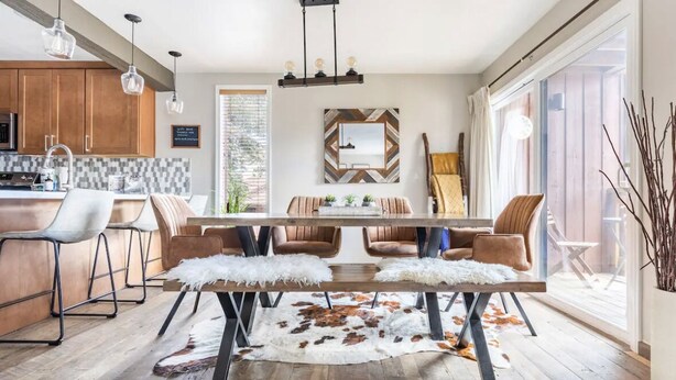 A modern dining area with a wooden table, leather chairs, and a cowhide rug. - Slopeside remodeled mountain cabin ski in ski out! (Mammoth Lakes)