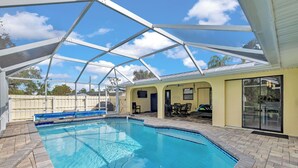 Una piscina con un portico coperto, un edificio giallo e un cielo azzurro intenso.