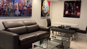 Een moderne woonkamer met een leren bank, glazen bijzettafels en kunstwerken aan de wanden.