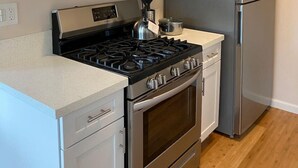 Une cuisine moderne dotée d’appareils électroménagers en acier inoxydable, de meubles blancs et d’un plancher en bois.