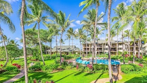 Un resort con piscina, palmeras y un jardín bien cuidado.