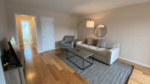 Un salon comprenant un canapé, un fauteuil, une table basse et un meuble pour la télévision.