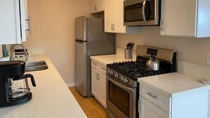 Une cuisine moderne équipée d’appareils électroménagers en acier inoxydable, notamment un réfrigérateur, un four à micro-ondes, une cuisinière et une machine à café.