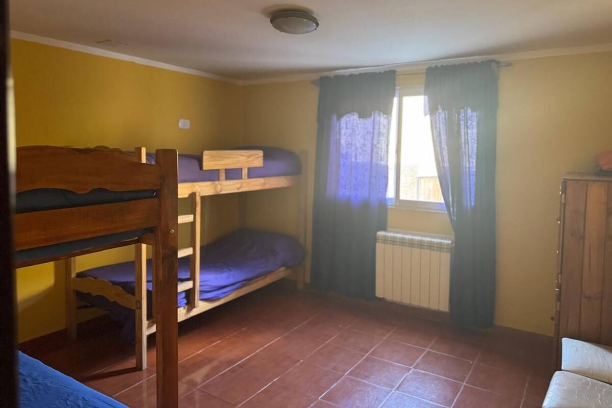 Una habitación con literas, un radiador y una ventana con cortinas.