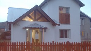 Une maison à deux étages, avec une façade blanche, une clôture en bois et une porte de garage bien visible.