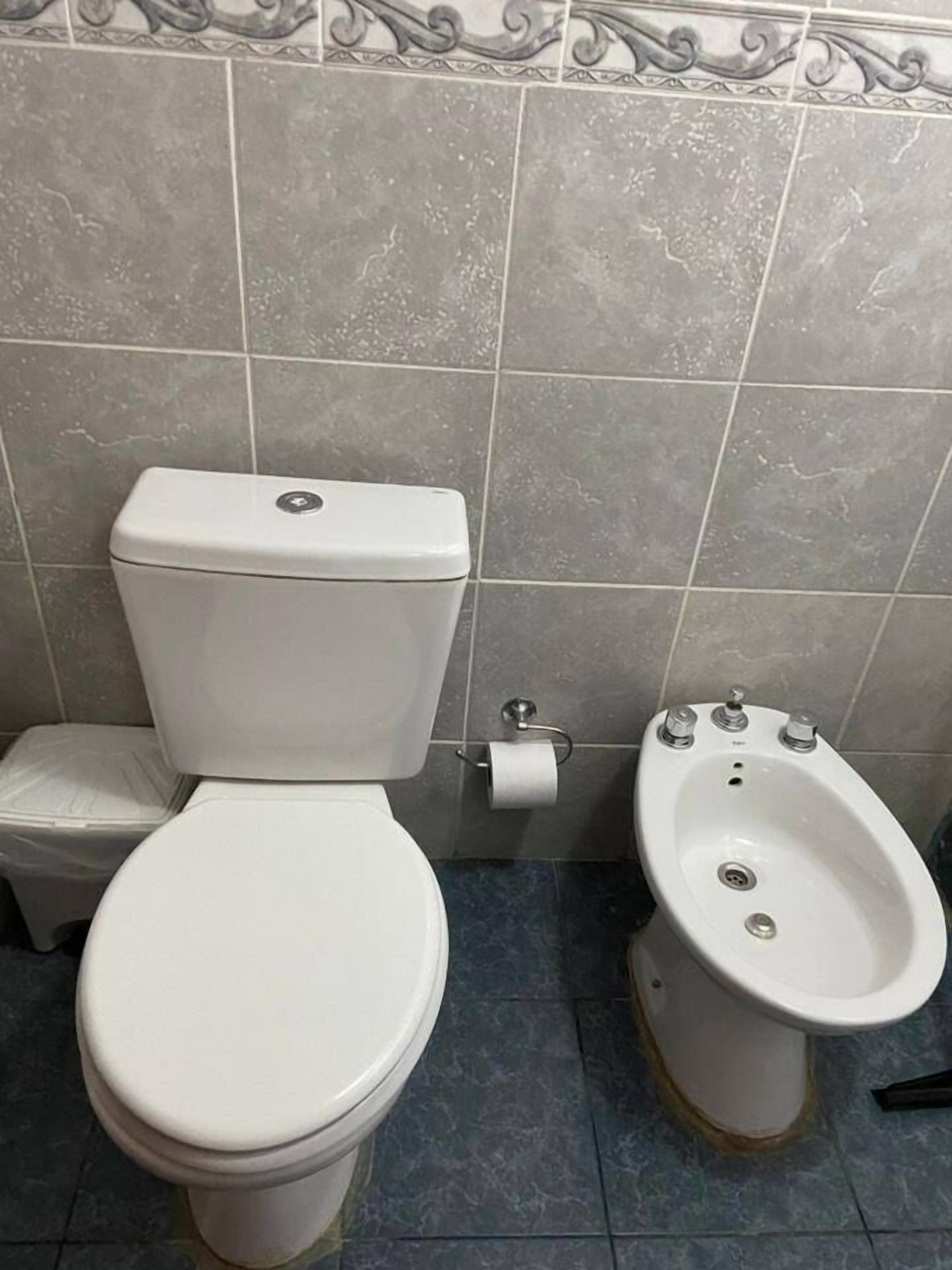 Un bagno con il water, un bidet e un piccolo cestino.
