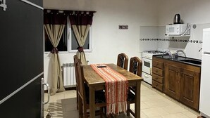 Une cuisine compacte comprenant une table à manger, des placards en bois, un four à micro-ondes et une cuisinière.