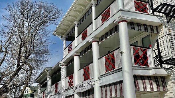 A multi-story building with a prominent sign reading "Quaker Inn" at the ground level. - Quaker Inn (Ocean Grove)