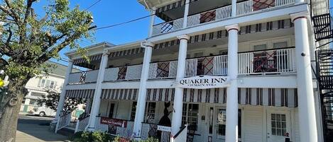 A two-story Quaker Inn with a central entrance, multiple balconies, and a classic architectural style.
