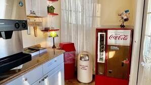 A compact kitchen with a coffee maker, a refrigerator, and a recycling bin. - Quaker Inn (Ocean Grove)