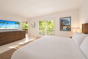 Un dormitorio con una cama grande, televisión, cómoda, ventana con persianas y un cuadro enmarcado en la pared.