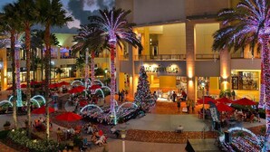 Un vestíbulo de hotel con un árbol de Navidad, palmeras y zonas de estar al aire libre.