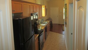 A kitchen with wooden cabinets, a black refrigerator, a microwave, and a sink.