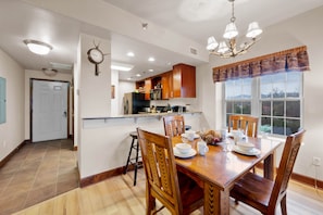 Enjoy meals with family and friends in this well-appointed dining area, featuring a table for four and a kitchen in the background.