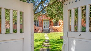 Un sendero que lleva a un edificio con fachada roja y puerta blanca.