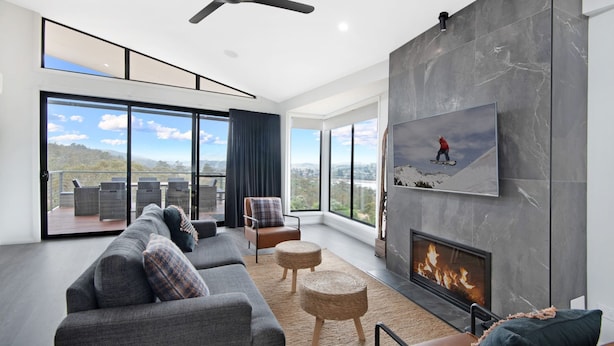 A modern living room with a fireplace, large windows, and a balcony with outdoor furniture.