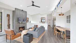 A modern living room with a fireplace, sofa, and dining area.