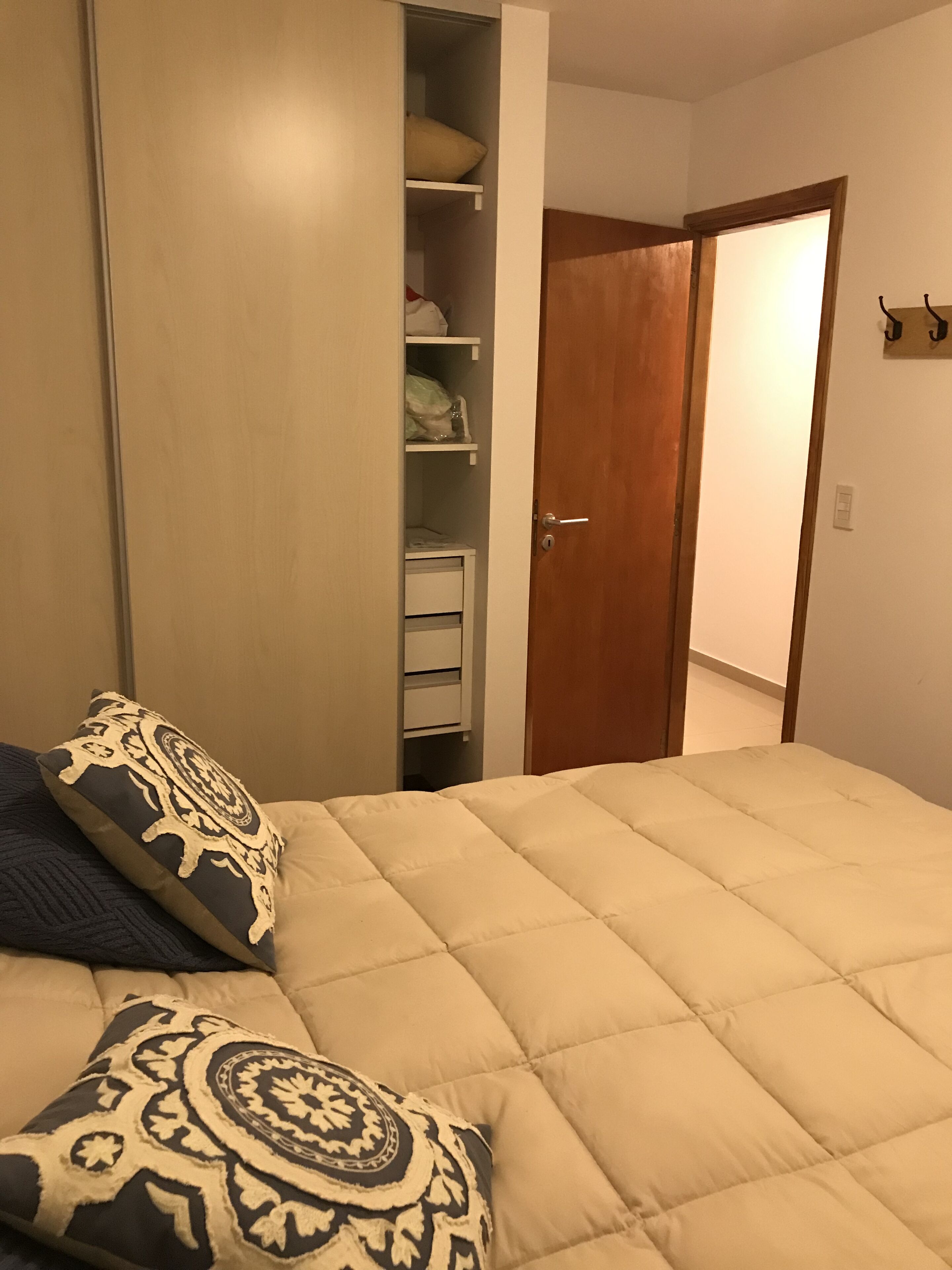 Quarto com cama, guarda-roupa e porta.