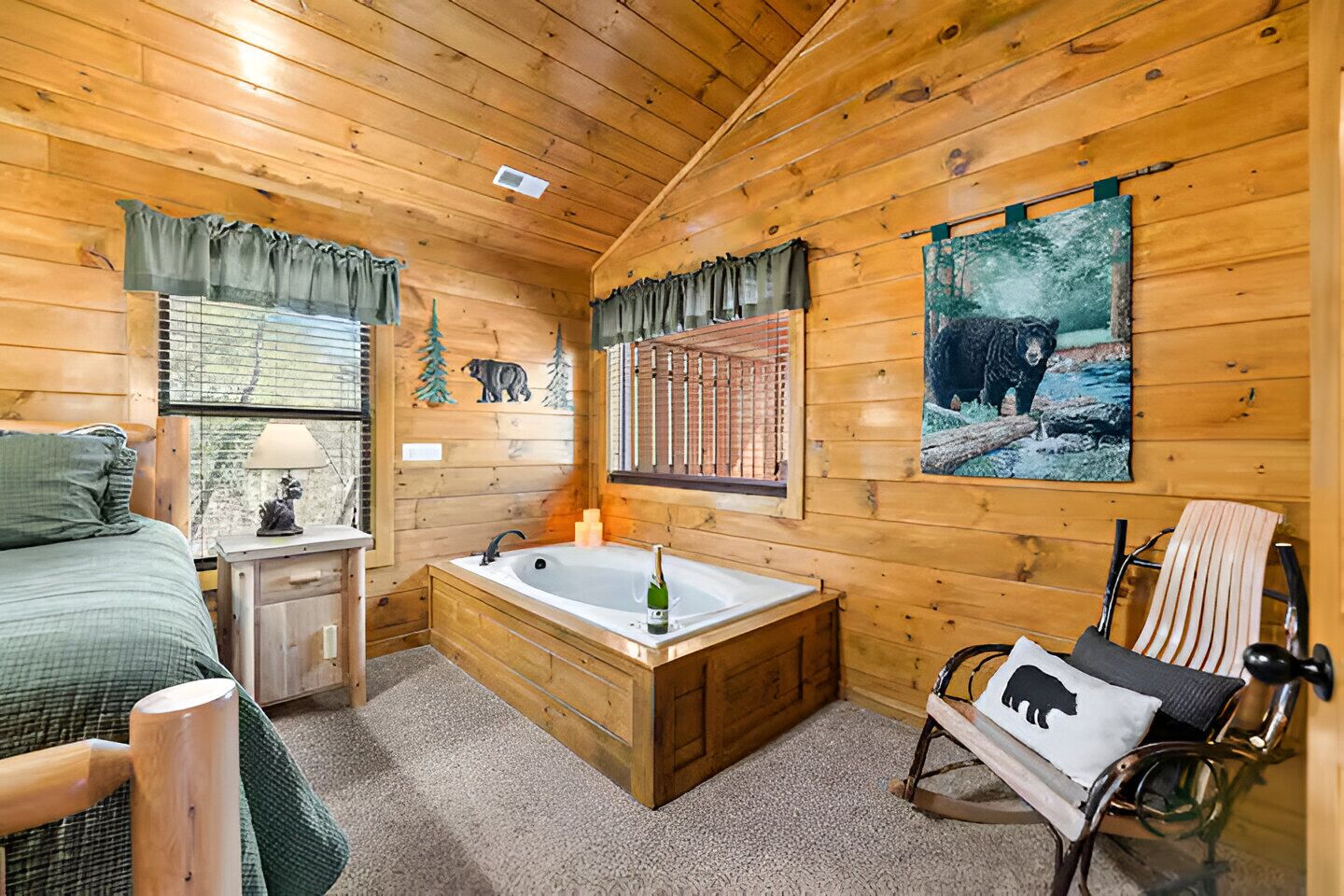 Ein gemütliches Blockhauszimmer mit einem Bett, einem kleinen Tisch mit Lampe, einer Holzbadewanne und einem Schaukelstuhl.