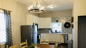 A kitchen with white cabinets, a stainless steel refrigerator, a dining table with chairs, and a chandelier. - Bourbon Country Cottage <br>Newly renovated  in the country with amazing views (Mount Eden)