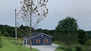 A single-story house with a dark blue exterior, a gravel driveway, and a small porch. - Bourbon Country Cottage <br>Newly renovated  in the country with amazing views (Mount Eden)