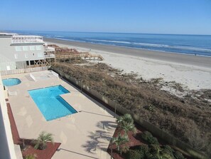 A beachfront hotel with a swimming pool, beach access, and a view of the ocean.