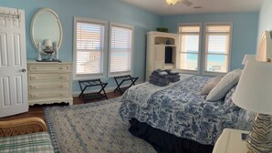 A bedroom with a bed, dresser, and a window with blinds.