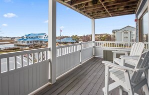 A covered porch with white railings and Adirondack chairs, overlooking a body of water and buildings. - Beautiful 2 BR 2 BA Unit in the Popular Harbour Club Community! (Ocean City)
