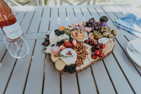 A charcuterie board with various cheeses, fruits, and nuts on a wooden table.