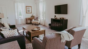 Un salon comprenant un canapé, un fauteuil, une table basse et un téléviseur fixé au mur.